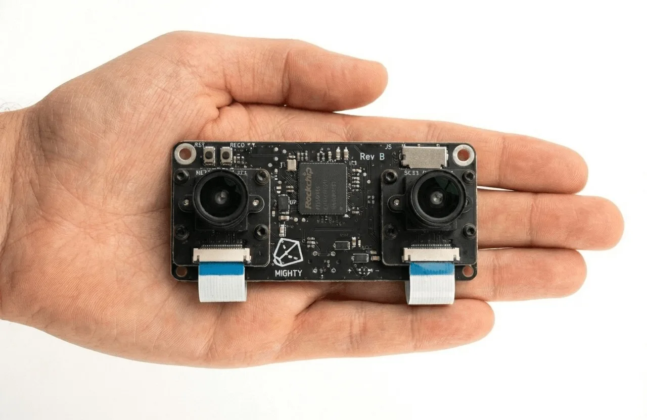 Beacon SLAM module held in hand: dual global-shutter cameras flanking an ARMv7 SoC on a board the size of a finger pad