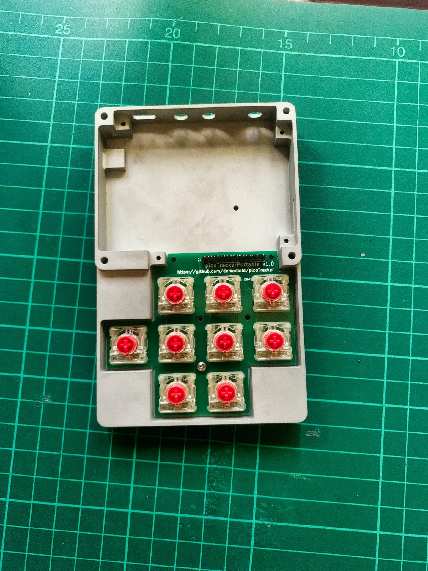 A DIY mechanical keypad circuit with red switches on a green cutting mat.